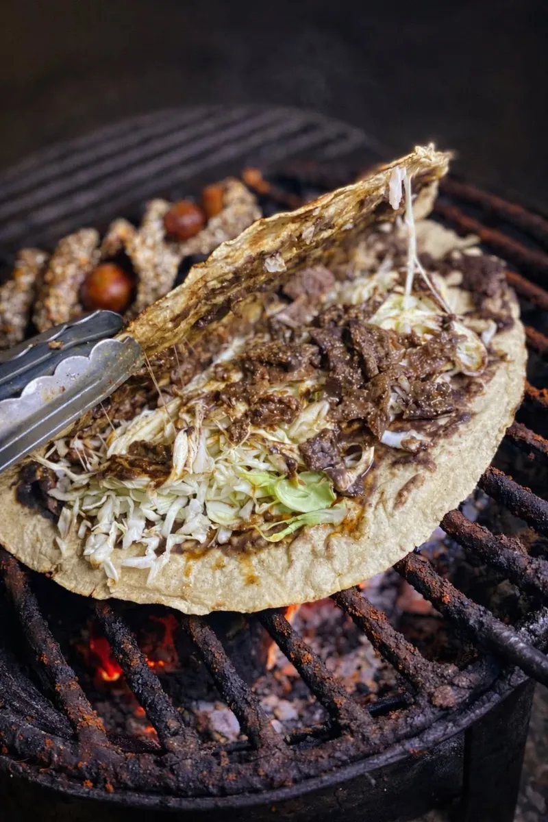 Tlayuda oaxaqueña asándose sobre brasas